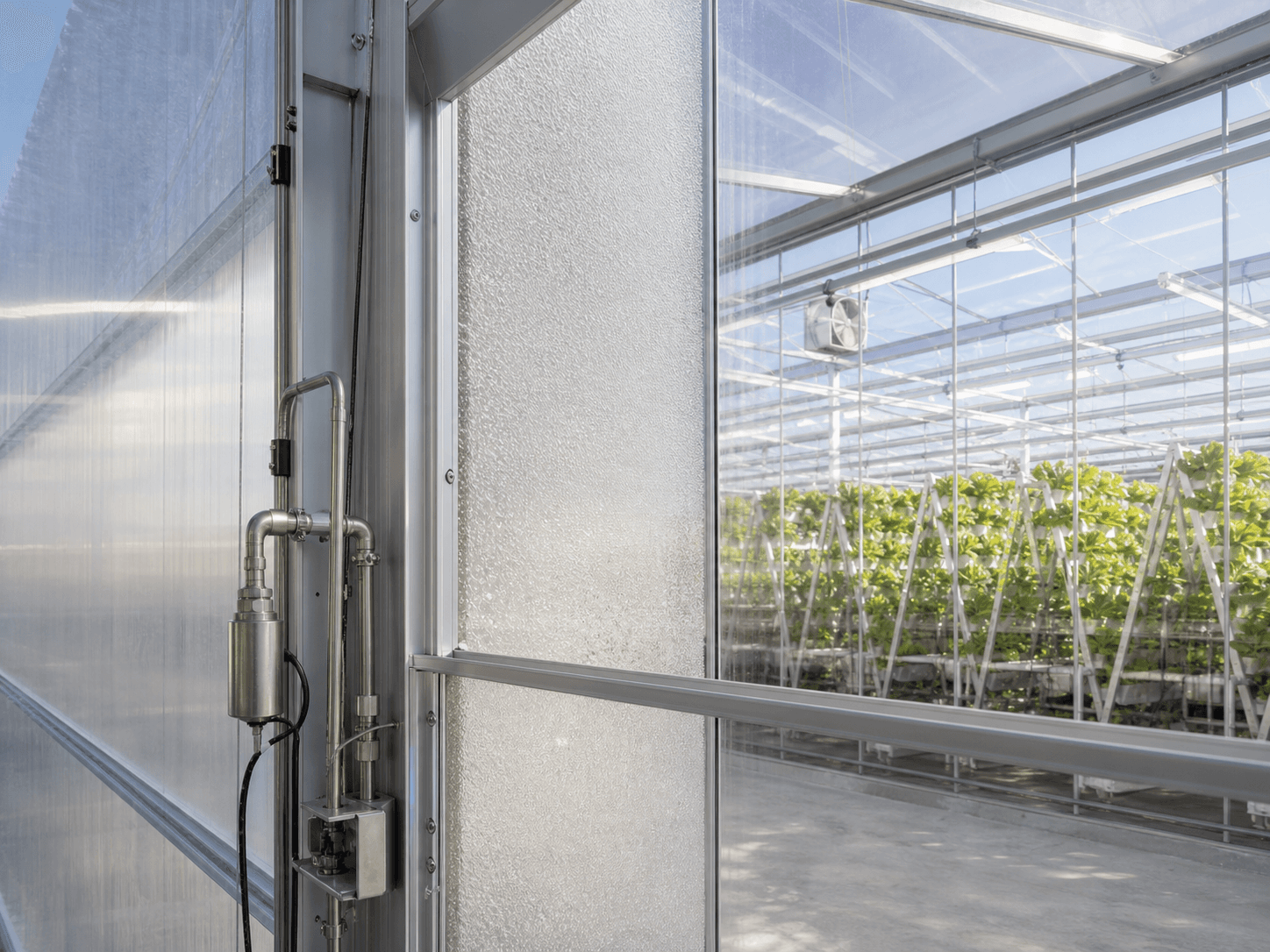 Close-up of a bubble-insulated double-membrane greenhouse wall with misting and control hardware